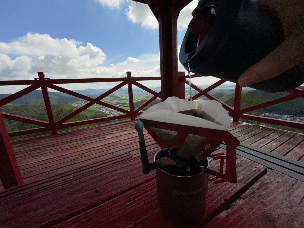 三峰山の景色を眺めながらコーヒーをハンドドリップする様子
