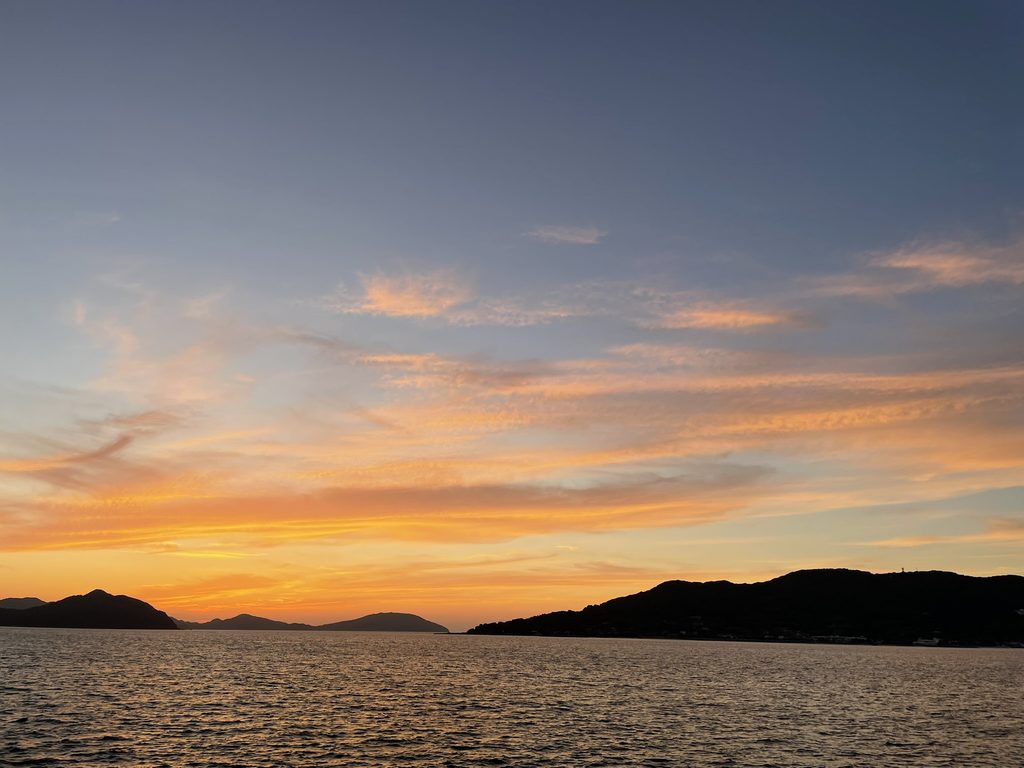 小戸公園から眺めた、海と山並みの上に広がるオレンジ色の夕焼け