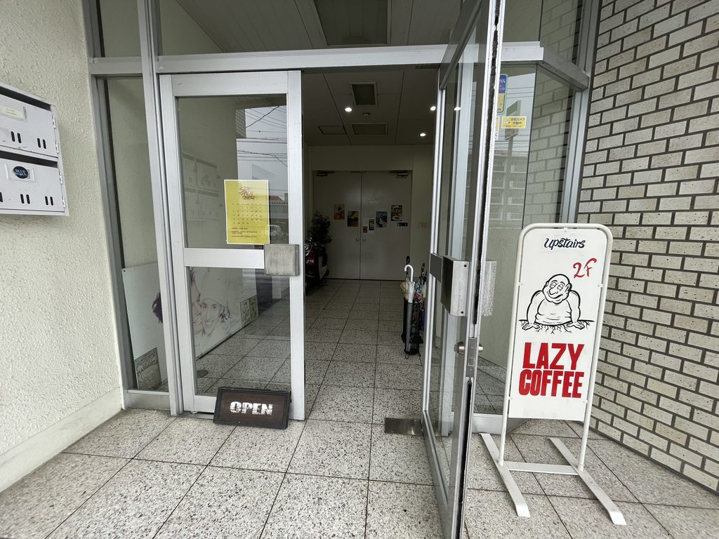 LAZY COFFEEの2階へ案内する建物入口の看板